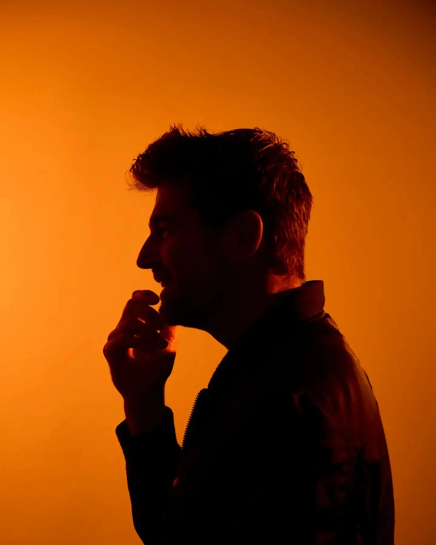 Alejandro Zárate in silhouette against an orange backdrop