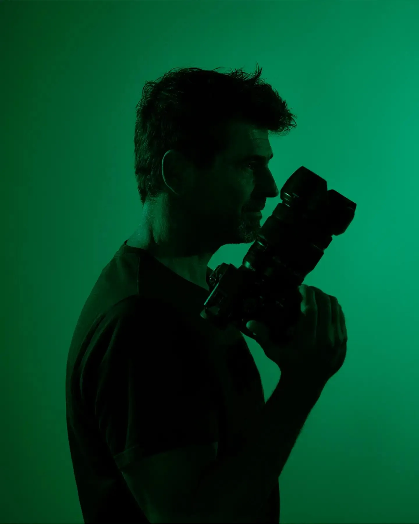 Alejandro Zárate holding a camera against a green backdrop